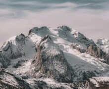 Snow-covered mountain range under cloudy sky Snowy mountain peaks with cloudy sky