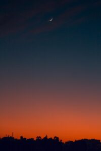 Fiery sunset with crescent moon Crescent moon and fiery orange sunset horizon