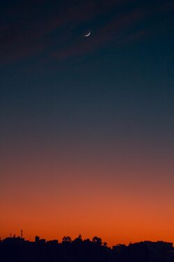 Fiery sunset with crescent moon Crescent moon and fiery orange sunset horizon